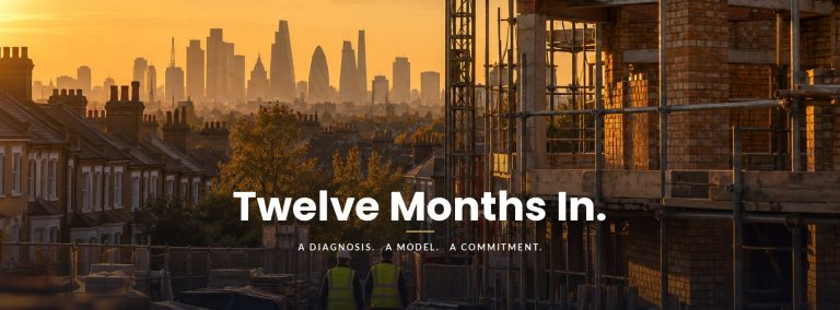 Blog A part-built brick building behind scaffolding among South London terraced houses at sunrise, the City of London skyline hazy behind, two workers walking the site. Overlaid: Twelve Months In. A diagnosis. A model. A commitment.