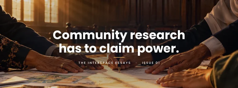Community research has to claim power. The Interspace Essays, Issue 01. Hands of different ages rest together on maps across a sunlit table, two of them holding one pen.